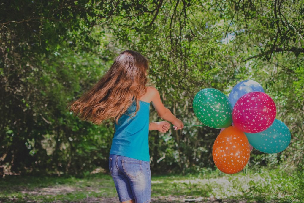Petite fille jouant avec des ballons colorés dans un jardin