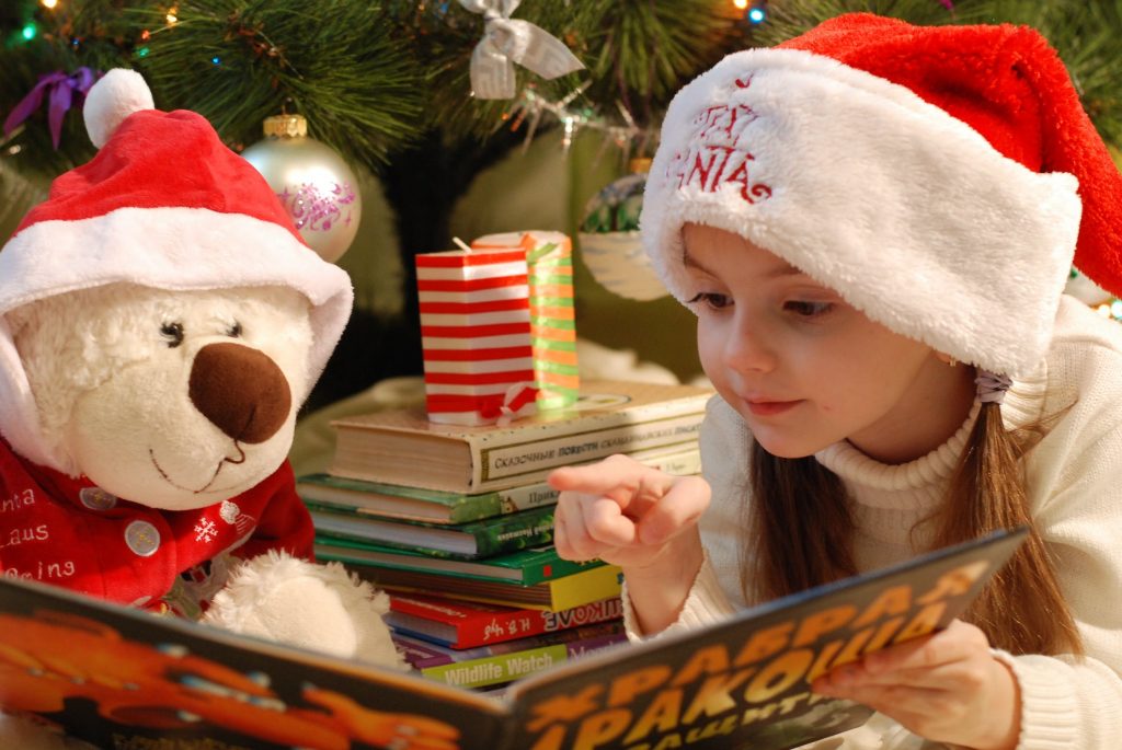 Petite fille qui joue avec ses cadeaux de Noël au pied du sapin